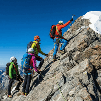 Mountain Climbers Roped Together Ascending Peak with blue skies in background