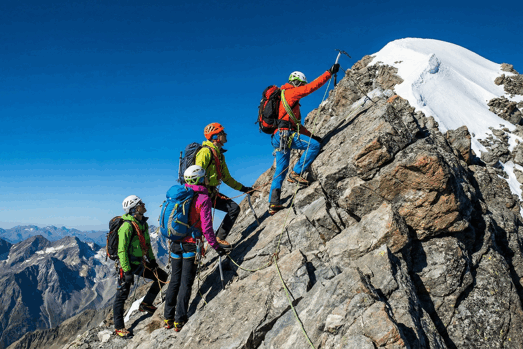 Mountain Climbers Roped Together Ascending Peak with blue skies in background