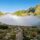 A trail through a mountain pass with fog ahead and clear sky behind — the cost of sitting in cash and finding the path forward, Riverwater Partners