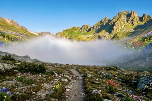 A trail through a mountain pass with fog ahead and clear sky behind — the cost of sitting in cash and finding the path forward, Riverwater Partners